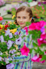 Naklejka premium Lovely girl holding flowers in garden center.
