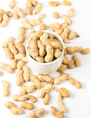 Raw shelled great peanuts in a cup on white background, closeup