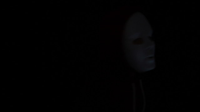 Horror masked man with torch in darkness