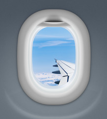 airplane window with wing and cloudy sky behind © Andrey Kuzmin