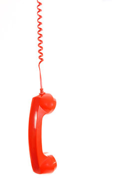 Isolated dangling red retro telephone receiver on white