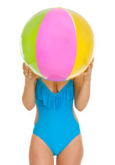 Young woman in swimsuit hiding behind beach ball