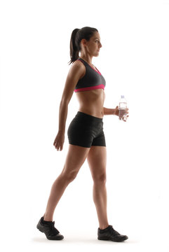 Mujer deportista caminando y sujetando botella de agua.