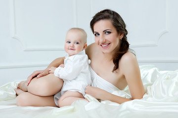 Happy family. Mother and her baby son playing and smiling on bed