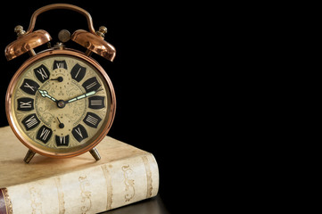 old alarm clock and antique book. it's time to wake up