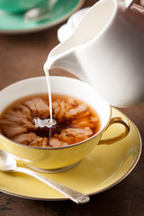 Pouring milk on a tea cup