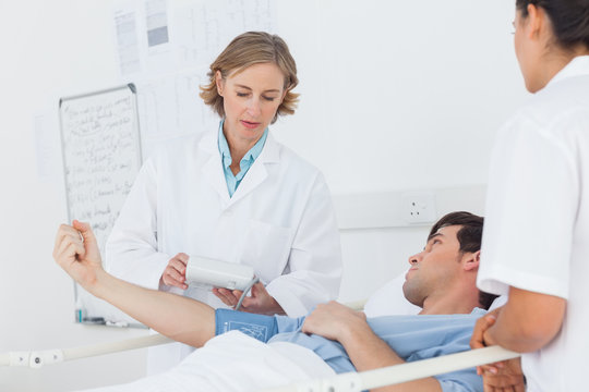 Doctor taking the blood pressure of male patient