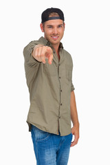 Fototapeta premium Man smiling and wearing baseball hat backwards and pointing