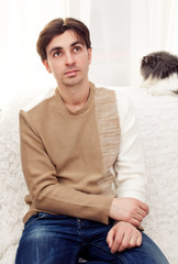 Handsome man sitting on the sofa. Closed pose