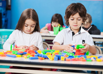 Children Playing With Construction Blocks In Classroom