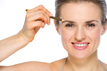 Beauty portrait of happy young woman applying brown eye liner