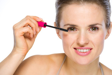 Beauty portrait of happy young woman applying mascara