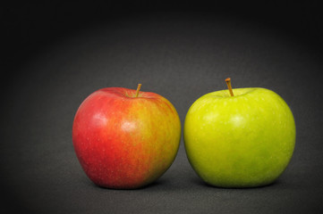 Red and green apples on a dark table