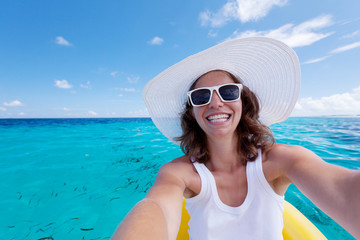 Woman makes photo of herself against blue ocean