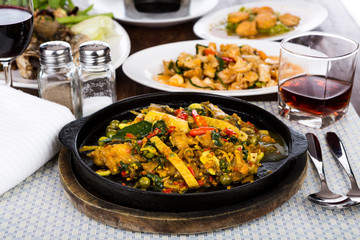 Fried fish with fresh herbs and  spicy sauce served on iron hot