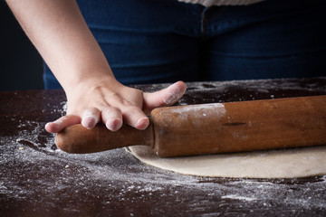 Hand on a rolling pin preparing pizza dough