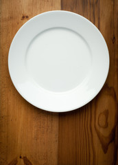 Empty white plate on wooden table