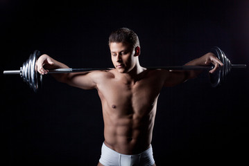 Portrait of attractive guy posing with barbell