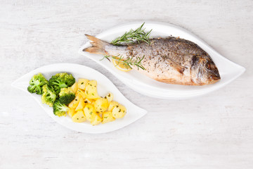 Grilled sea bream with potatoes on plate.