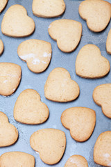 Fototapeta na wymiar Rows of heart shaped biscuits on metal baking tray