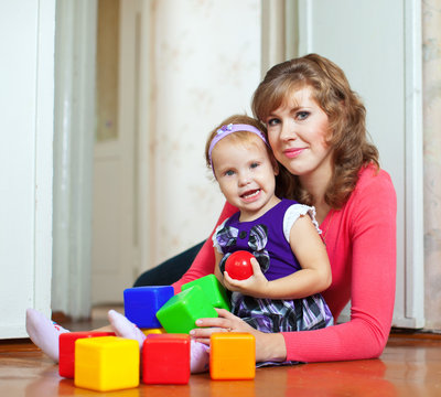 Happy mother and baby plays with blocks