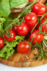 Fototapeta na wymiar Fresh cherry tomatoes and salad in a wooden plate