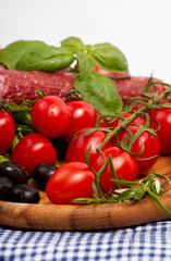 Fresh cherry tomatoes and salad in a wooden plate