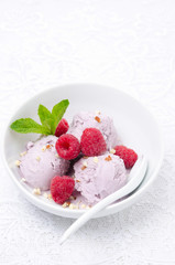 ice cream with fresh raspberries and mint in a white bowl