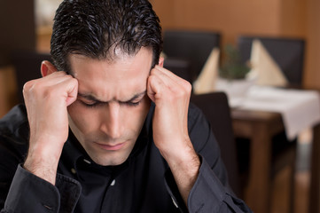 Mann mit Kopfschmerzen im Restaurant