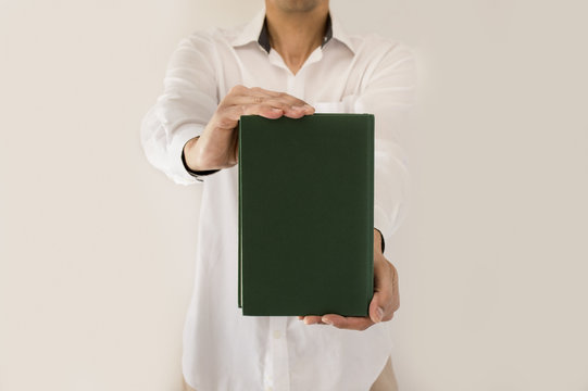Man Holding Up Book With Green Empty Book Cover In Close-up