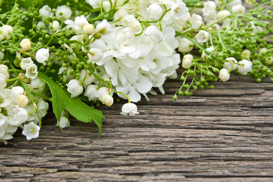 Bottle with essential oil and lily-of-the-valley flowers on white