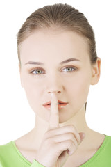 Naklejka premium Hush be quiet woman isolated. Teen girl with finger on her lips.