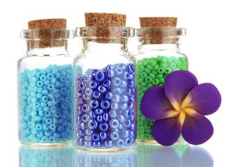 Little bottles full with colorful beads isolated on white