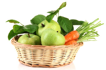 Juicy green apples and carrots with leaves in basket, isolated