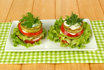 Tasty roasted marrow and tomato slices with salad leaves,