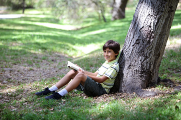 Young boy reading a book  in the woods