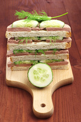 Sandwiches with liver sausage and cucumber on cutting board
