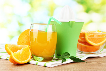 Citrus press, glass of juice and ripe oranges