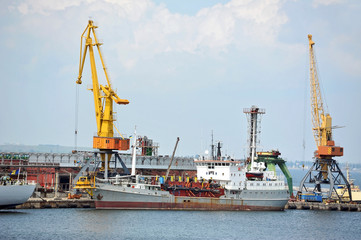 Industrial ship under crane bridge in harbor