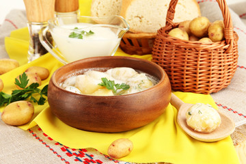 Tender young potatoes with sour cream and herbs in wooden bowl