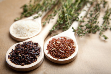 Red and white rice on wooden spoons