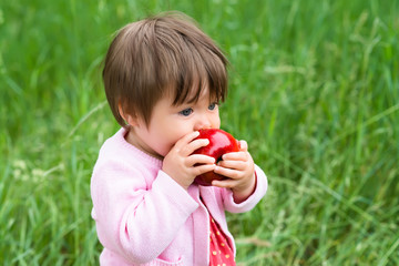 little girl eating an apple outdoors