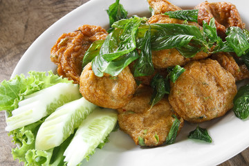 fried mackerel paste balls with vegetable for food in white plate and wood table