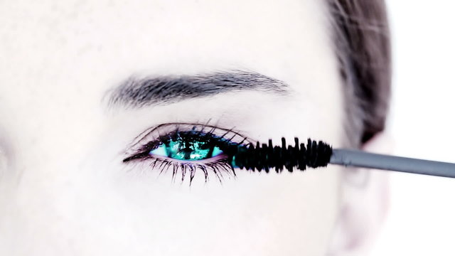Blue eyed woman making up with mascara