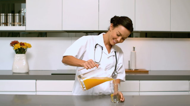 Home nurse pouring orange juice in kitchen