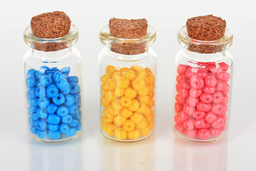 Different colorful beads in bottles isolated on white