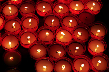 Candele votive rosse illuminano il buio in chiesa