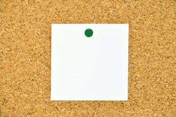 Zettel mit grünem Pin an Korkwand