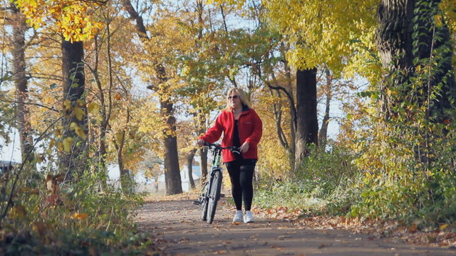 woman with a bicycle is in the autumn park