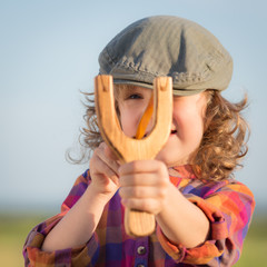 Funny kid shooting wooden slingshot